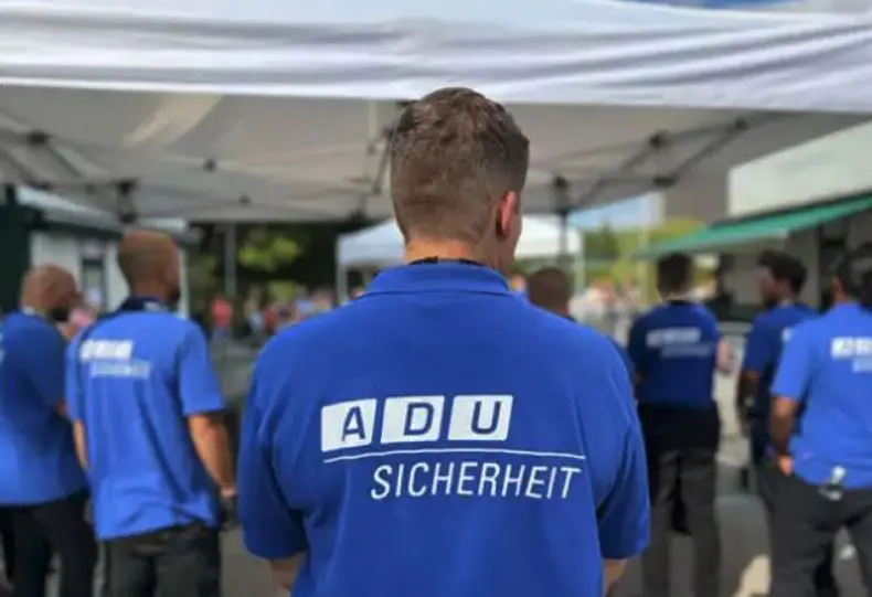 Rücken von ADU-Sicherehitsdienstmitarbeitern, die gerade ein Festival bewachen und schützen
